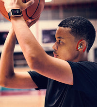 A young man or a teen playing basketball, while wearing apple products and accesories, as well as red AirPod pro Earhooks.
